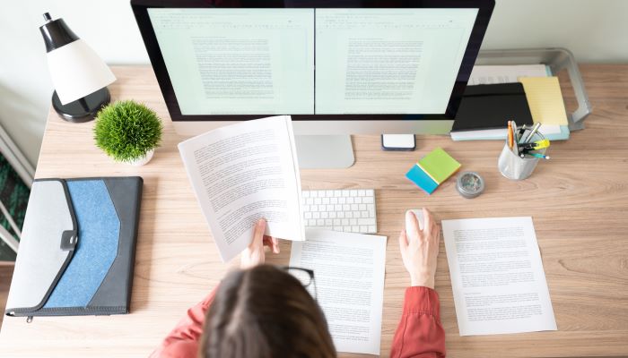 Person holding up a piece of paper in front of a computer screen